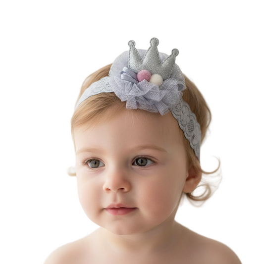 Baby wearing a decorative headband with a crown on a white background
