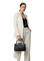Load image into Gallery viewer, Woman in a beige suit holding a black handbag on a white background
