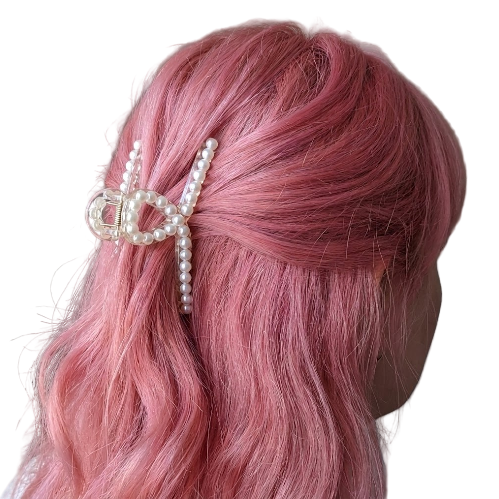 Mannequin head with pink hair and a decorative hair clip on a white background